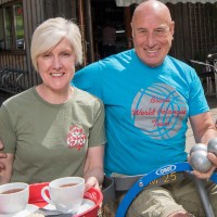 Lesley Johnston, owner of the Broch Cafe in Strathyre, carries a tray of tea and smiles to the camera on a sunny day