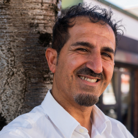 A man smiling by a tree.