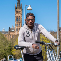 Man cycling/holding bike (cycle hire scheme). Cycle parking