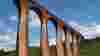 Red brick viaduct over river with trees on river bank and blue sky behind