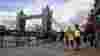 People walking alongside the Thames in front of Tower Bridge, London